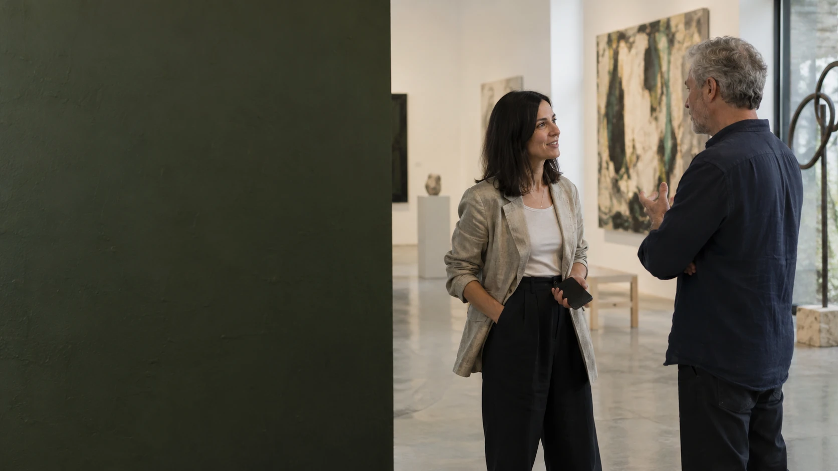 Two independent professionals meeting in a daylight art gallery